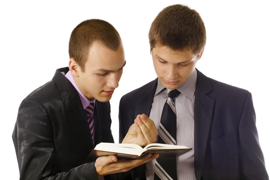 Young man explaining the bible to a teen boy during drug treatment