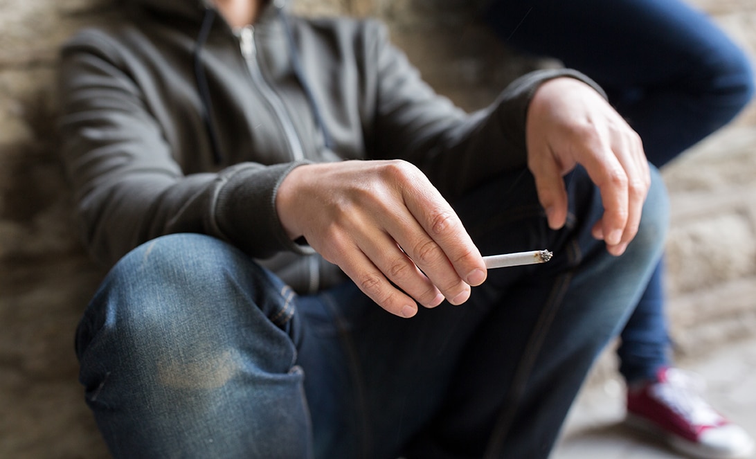 Young man holding a cigarette in need for drug treatment