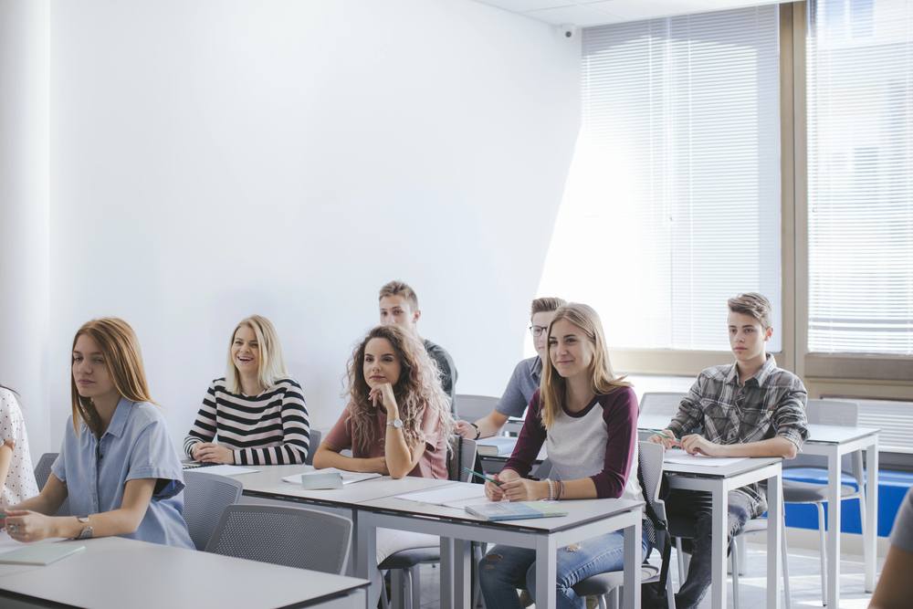 A teacher taking attendance and looking at an empty desk